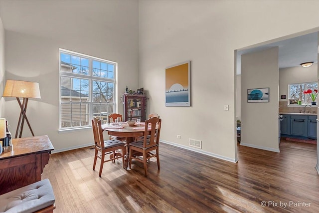 dining space featuring a high ceiling, sink, and dark wood-type flooring