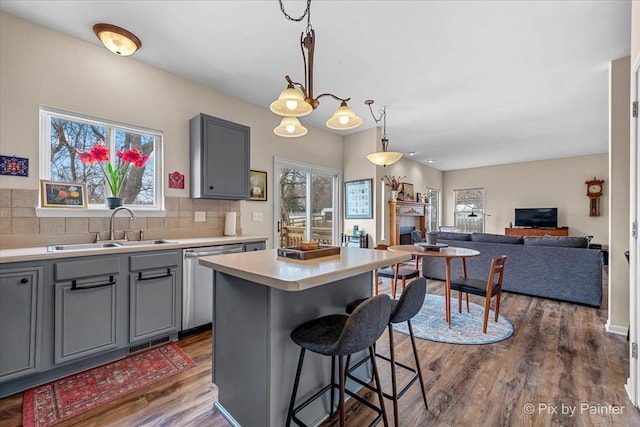 kitchen featuring a kitchen island, pendant lighting, sink, gray cabinetry, and stainless steel dishwasher