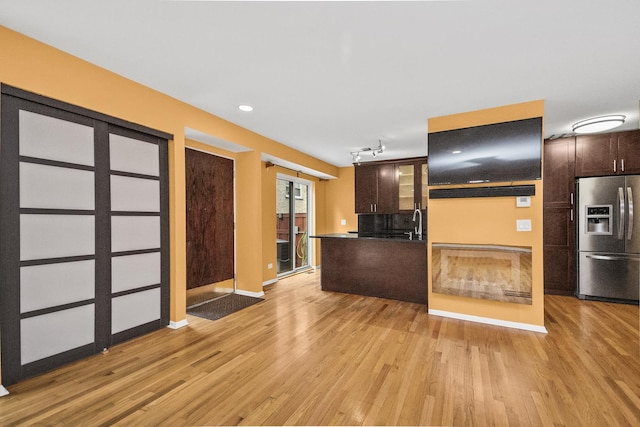 kitchen with light hardwood / wood-style flooring, stainless steel fridge with ice dispenser, dark brown cabinets, and sink