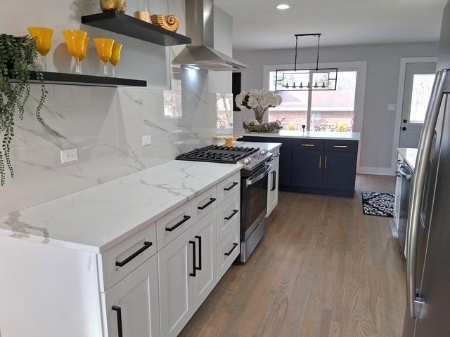 kitchen with wall chimney range hood, decorative backsplash, wood finished floors, gas stove, and open shelves