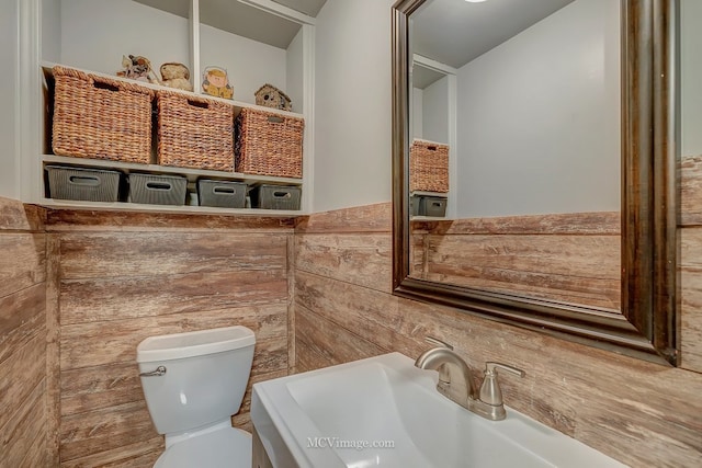 bathroom with sink, tile walls, and toilet