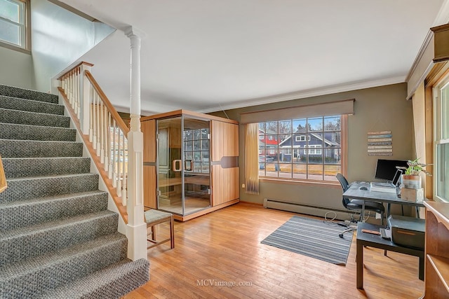 home office with baseboard heating, ornamental molding, light hardwood / wood-style floors, and decorative columns