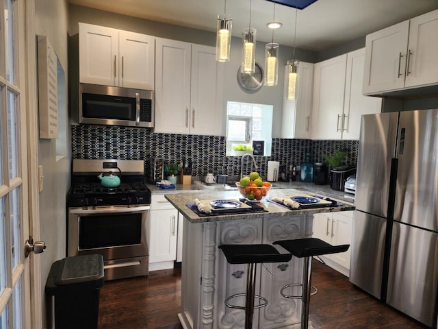 kitchen featuring pendant lighting, stainless steel appliances, light stone counters, tasteful backsplash, and white cabinets