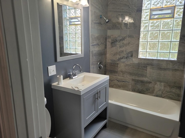 full bathroom featuring tiled shower / bath, vanity, toilet, and a wealth of natural light