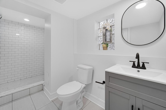 bathroom featuring tile patterned flooring, vanity, tiled shower, and toilet