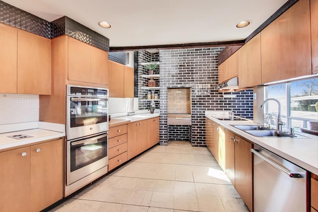 kitchen with light countertops, appliances with stainless steel finishes, backsplash, and a sink