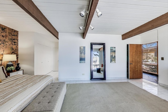 unfurnished bedroom with light tile patterned floors, baseboards, light colored carpet, beamed ceiling, and rail lighting