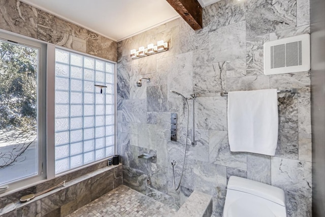 bathroom featuring toilet, a wealth of natural light, tiled shower, and visible vents