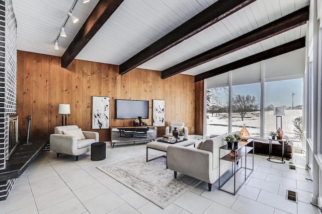 living area featuring wood walls, visible vents, beamed ceiling, and light tile patterned flooring