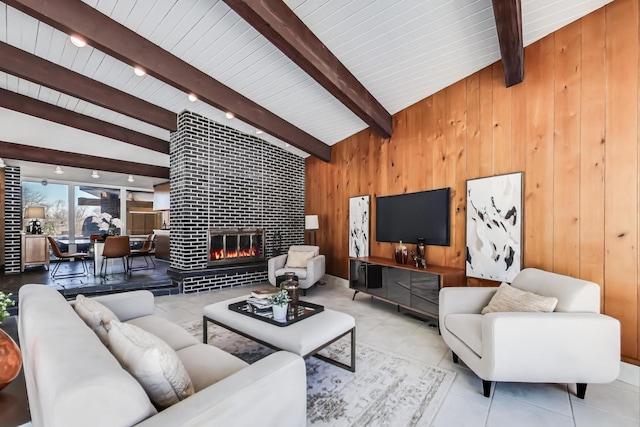 living area with light tile patterned floors, lofted ceiling with beams, wood walls, and a tiled fireplace