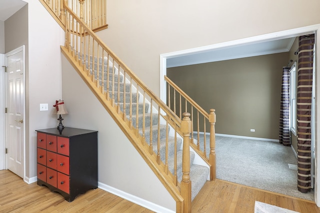 stairway featuring crown molding, a towering ceiling, and hardwood / wood-style floors