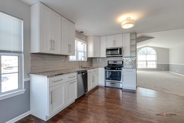 kitchen with appliances with stainless steel finishes, white cabinetry, sink, decorative backsplash, and light stone counters