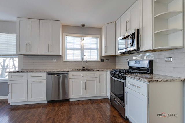 kitchen with white cabinetry, sink, light stone counters, and stainless steel appliances