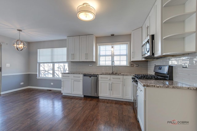 kitchen featuring decorative light fixtures, white cabinetry, sink, stainless steel appliances, and dark wood-type flooring