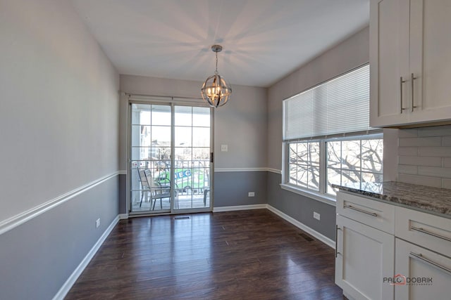 unfurnished dining area with dark hardwood / wood-style flooring, a wealth of natural light, and an inviting chandelier