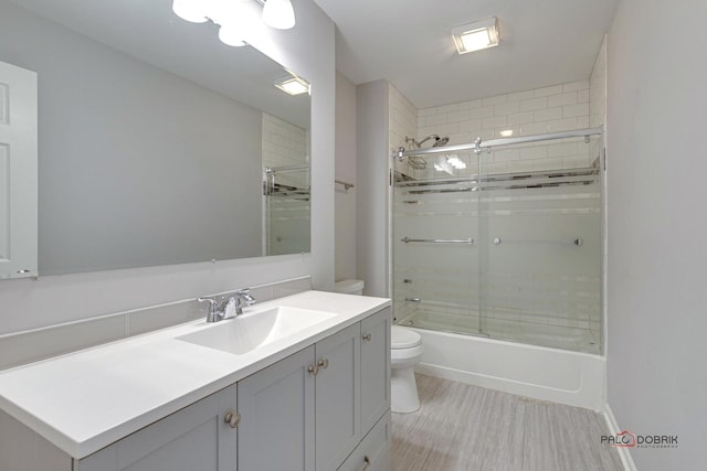 full bathroom with vanity, shower / bath combination with glass door, and toilet