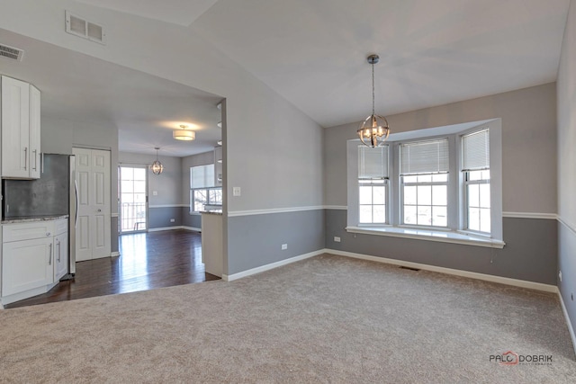 unfurnished room featuring dark colored carpet, vaulted ceiling, and a chandelier