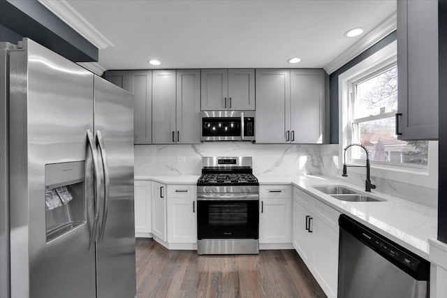 kitchen featuring sink, appliances with stainless steel finishes, gray cabinetry, dark hardwood / wood-style floors, and light stone countertops