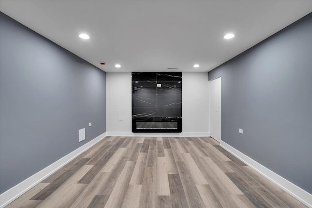 spare room featuring a large fireplace and light wood-type flooring