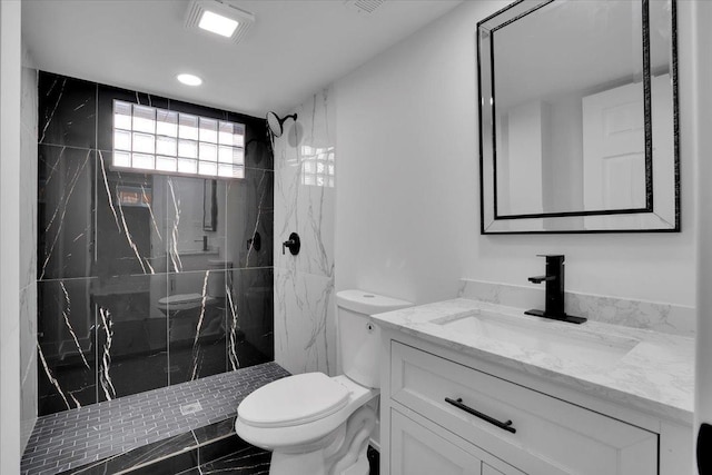 bathroom featuring vanity, toilet, and a tile shower