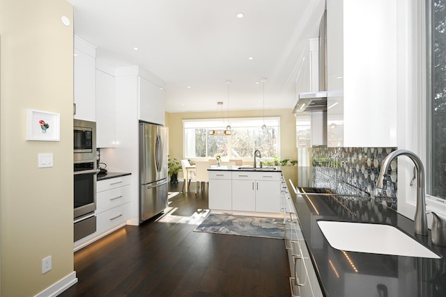 kitchen with dark wood-type flooring, sink, decorative light fixtures, appliances with stainless steel finishes, and white cabinets