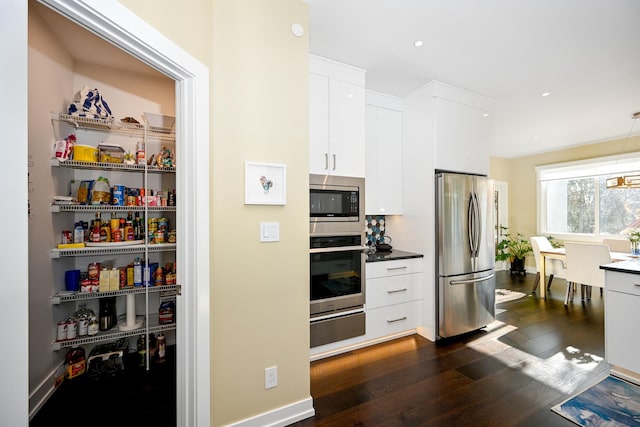 kitchen featuring pendant lighting, stainless steel appliances, dark hardwood / wood-style flooring, and white cabinets