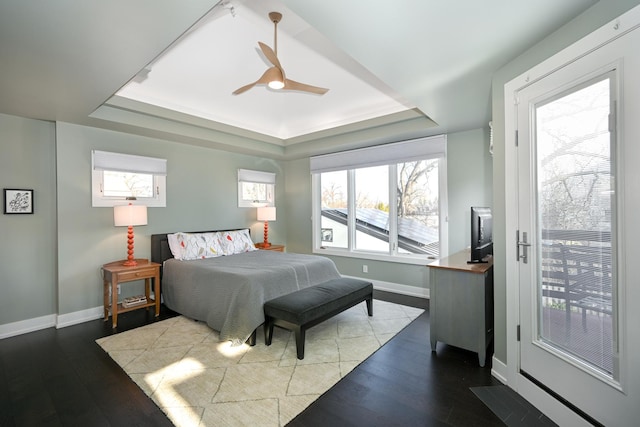 bedroom featuring ceiling fan, wood-type flooring, and a tray ceiling