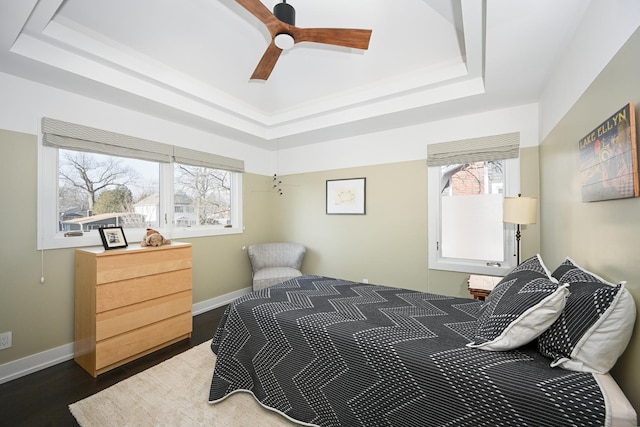 bedroom featuring dark hardwood / wood-style floors, a raised ceiling, and multiple windows