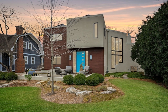 back house at dusk with a patio and a yard