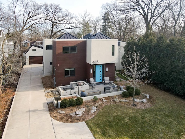 contemporary home featuring a patio, a front lawn, and a garage