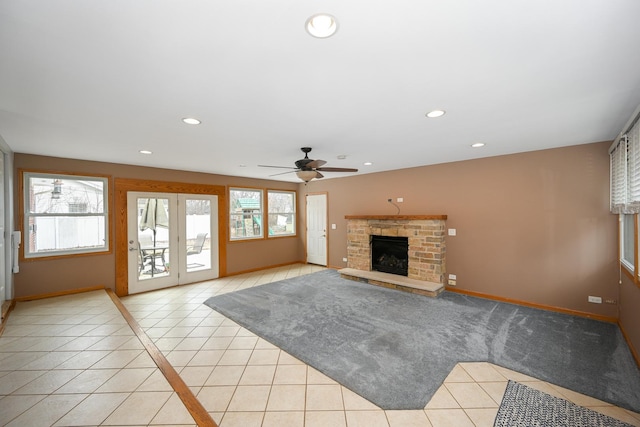 unfurnished living room featuring a stone fireplace, light tile patterned floors, and ceiling fan