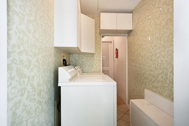 clothes washing area featuring light tile patterned flooring, cabinets, and washer and dryer