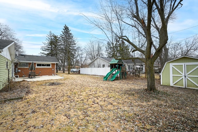 view of yard with a patio area, a playground, and a storage unit