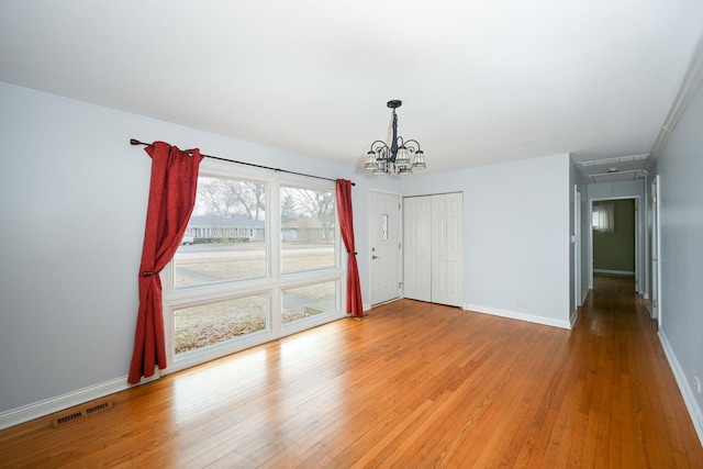 empty room featuring an inviting chandelier and light hardwood / wood-style floors