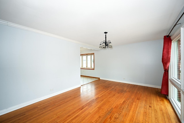 unfurnished room featuring a notable chandelier, crown molding, and light hardwood / wood-style floors