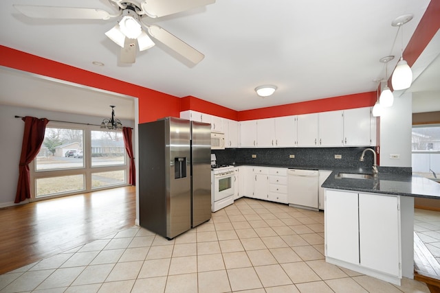 kitchen with sink, white appliances, tasteful backsplash, white cabinets, and kitchen peninsula