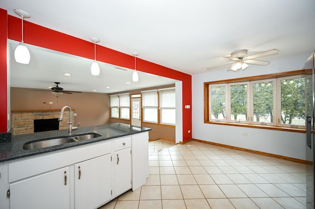 kitchen featuring hanging light fixtures, sink, white cabinets, and dark stone counters