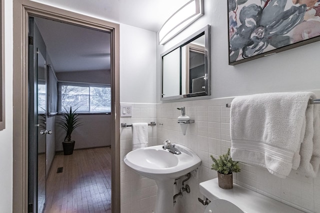 bathroom with hardwood / wood-style floors, lofted ceiling, tile walls, and toilet