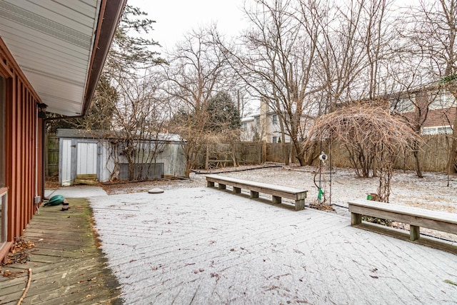 yard covered in snow with a storage unit and a deck