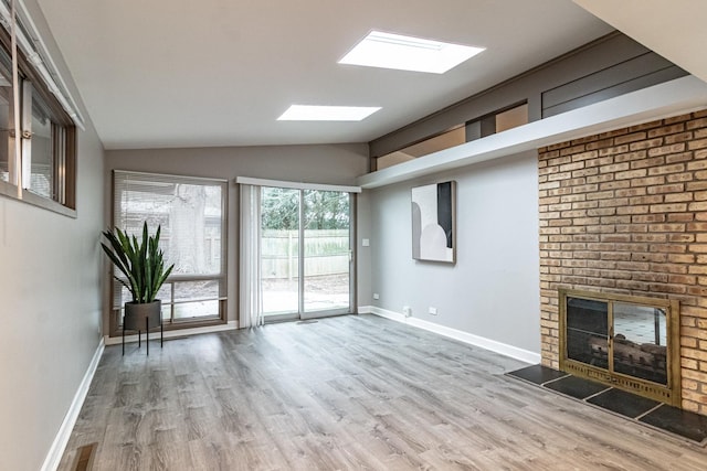 unfurnished living room featuring lofted ceiling, hardwood / wood-style flooring, and a fireplace