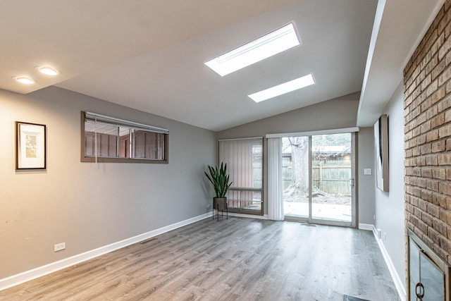 spare room featuring vaulted ceiling with skylight and light hardwood / wood-style flooring