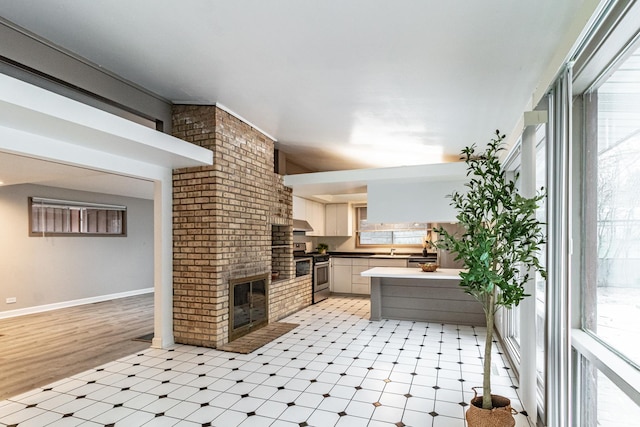 interior space with a wealth of natural light, stainless steel stove, a fireplace, and kitchen peninsula