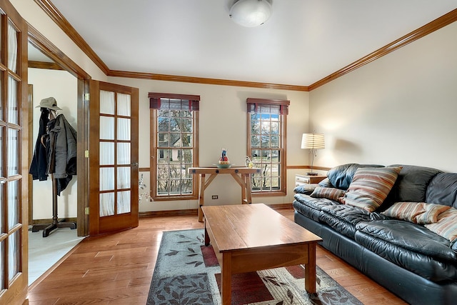 living room featuring ornamental molding, light wood-type flooring, and french doors