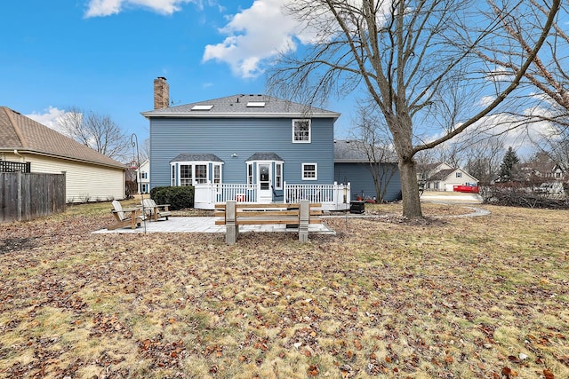 rear view of house with a wooden deck, a patio area, and a lawn