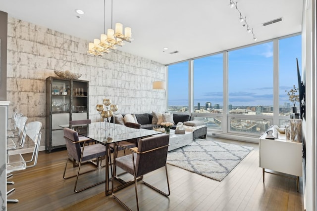 dining area with a wall of windows, a chandelier, wood-type flooring, and track lighting