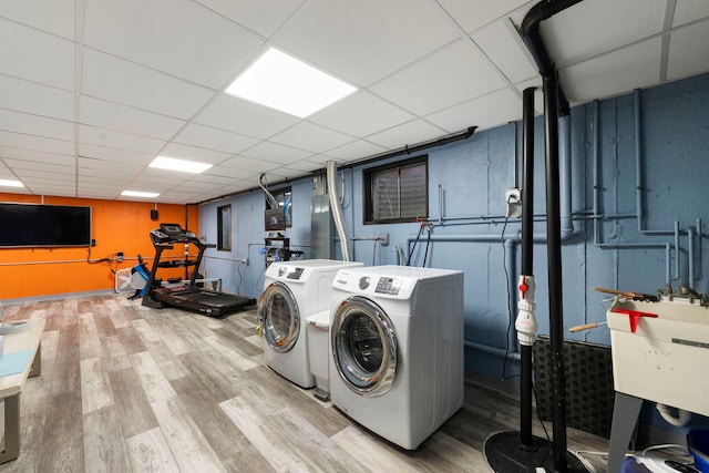 laundry area with light wood-type flooring, sink, and washer and clothes dryer