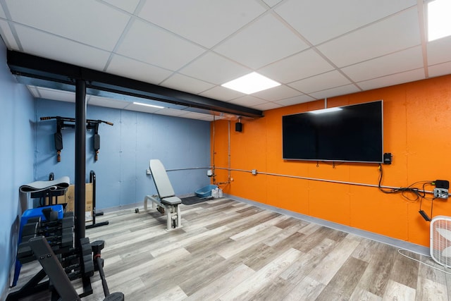 exercise room with a paneled ceiling and light hardwood / wood-style flooring