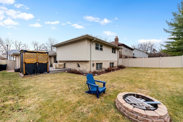 back of property with a lawn and an outdoor fire pit