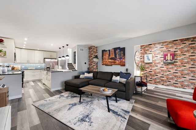 living room with brick wall and dark hardwood / wood-style flooring