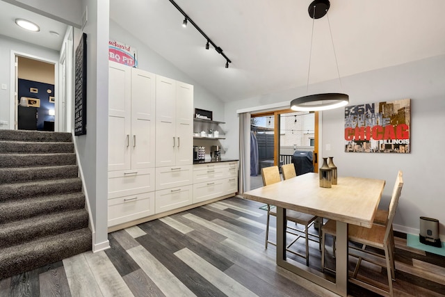 dining area with vaulted ceiling, track lighting, and dark hardwood / wood-style flooring